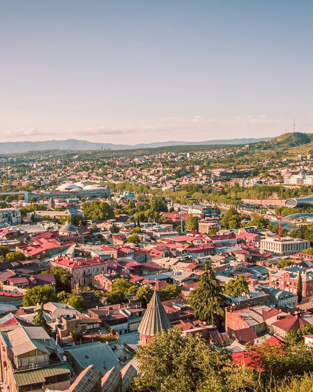 Tbilisi at sunset with the mountains behind